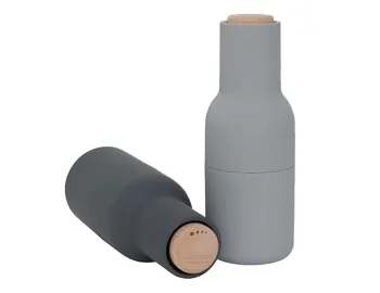 Dark grey Audo Bottle Grinder lying on its side to show the wooden adjustment lid beside a light grey grinder