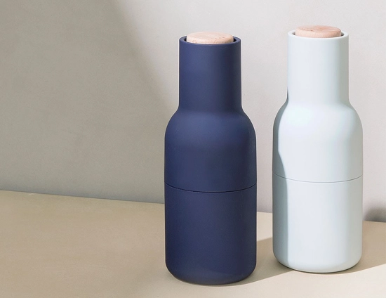 Navy and pale blue Audo Bottle Grinders with wooden lids standing together on a pale surface