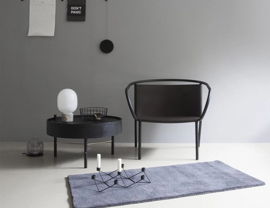 JWDA Concrete Table Lamp on a low black table beside a lounge chair and a blue rug