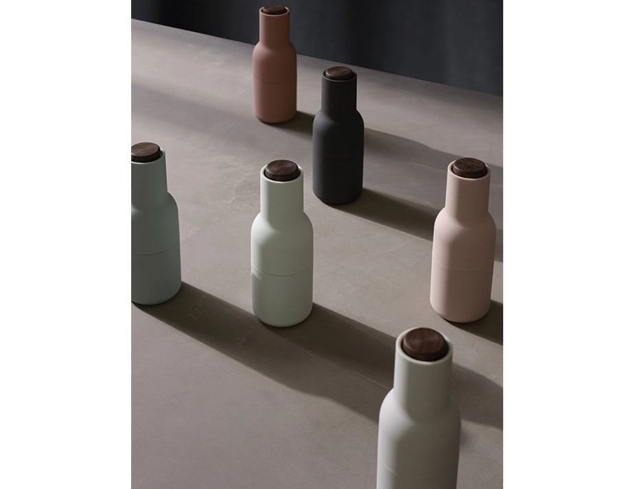 Six Audo Bottle Grinders in pastel pink, pale blue, grey and charcoal casting long shadows